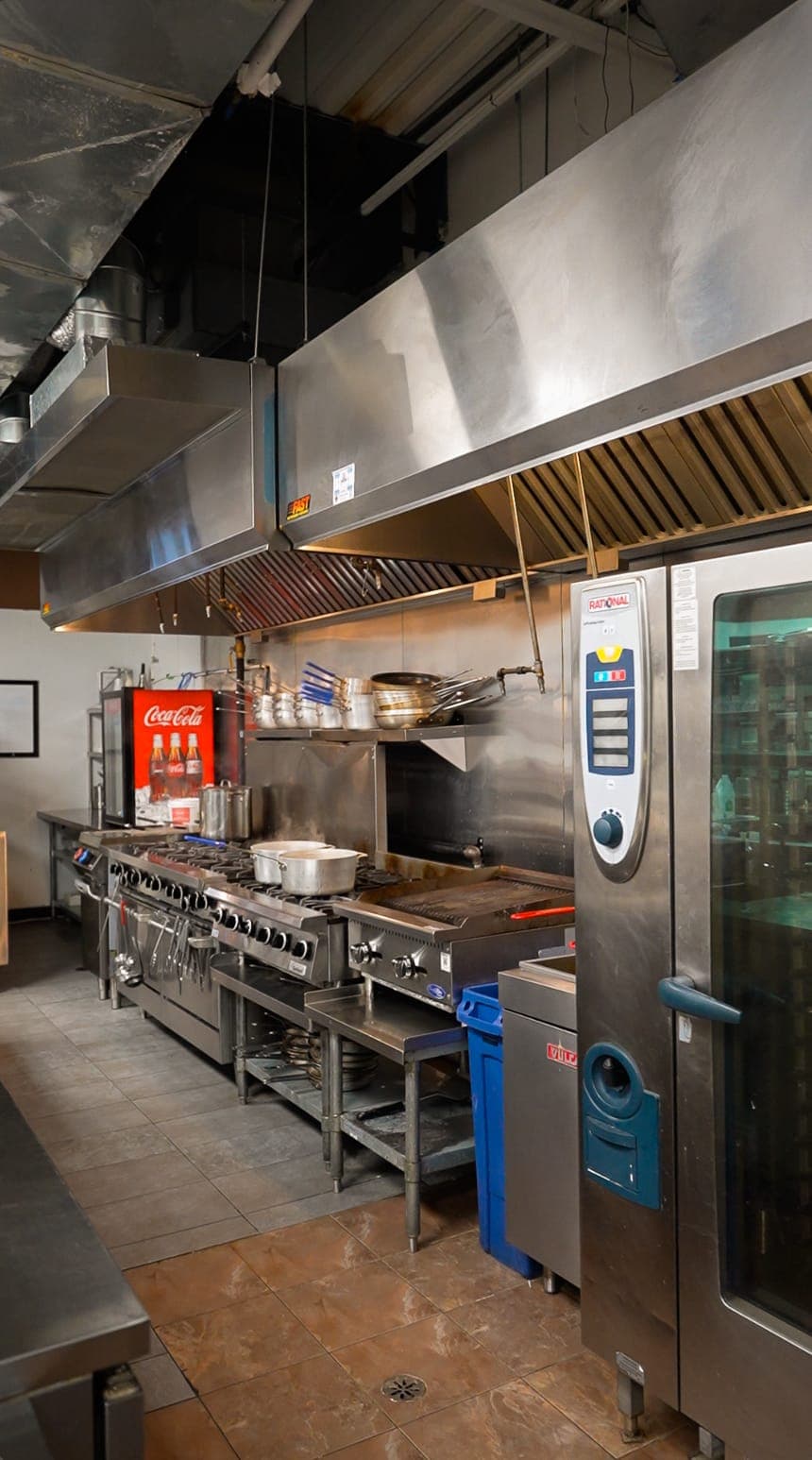 Commercial kitchen with stainless steel range and hood